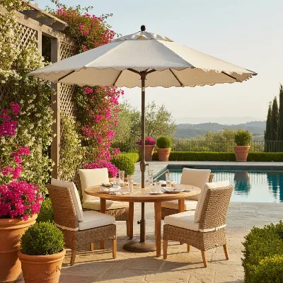 A luxurious outdoor patio featuring a large Frontgate Resort Collection market umbrella providing shade over a dining table. The setting is bright and inviting, with lush greenery in the background, showcasing the umbrella's elegant design and functional beauty in a resort-like atmosphere.