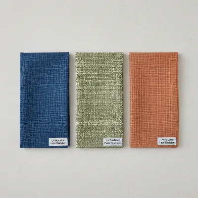 Close-up view of various patio umbrella fabric swatches with different textures and colors, showcasing quality materials